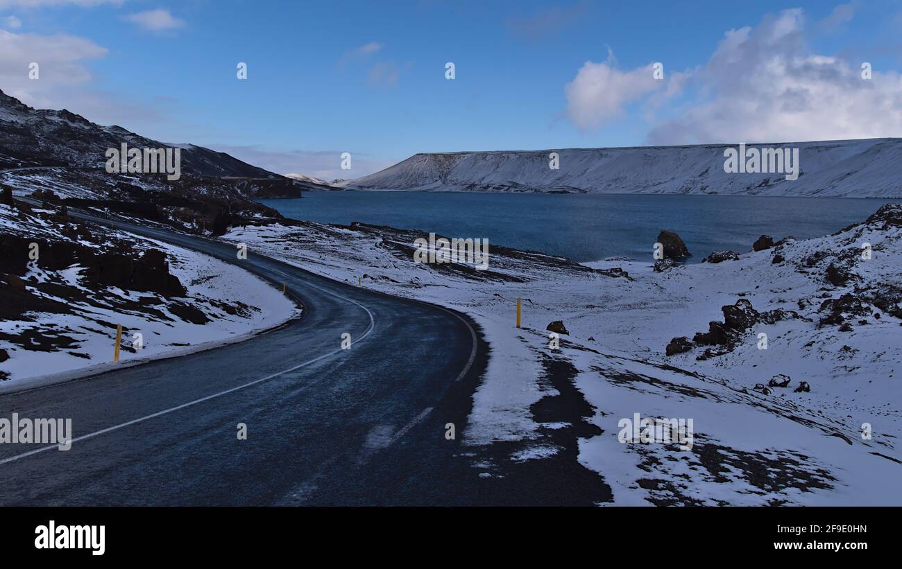 Belle vue sur la route pavée sinueuse de campagne sur la rive du lac Kleifarvatn à Krýsuvík, péninsule de Reykjanes, Islande entourée de montagnes. Banque D'Images
