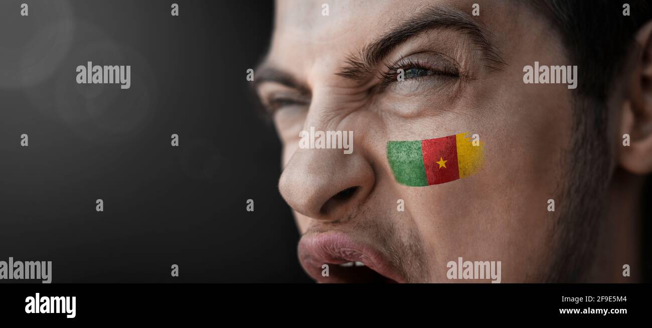 Un homme hurlant avec l'image du Cameroun national drapeau sur son visage Banque D'Images