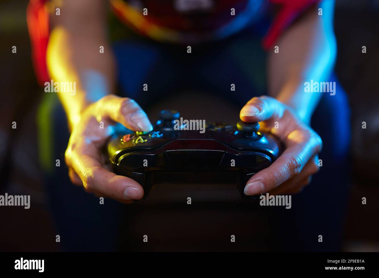 Rognez un joueur méconnaissable à l'aide du joy pad et jouez à un jeu vidéo dans la pièce sombre Banque D'Images