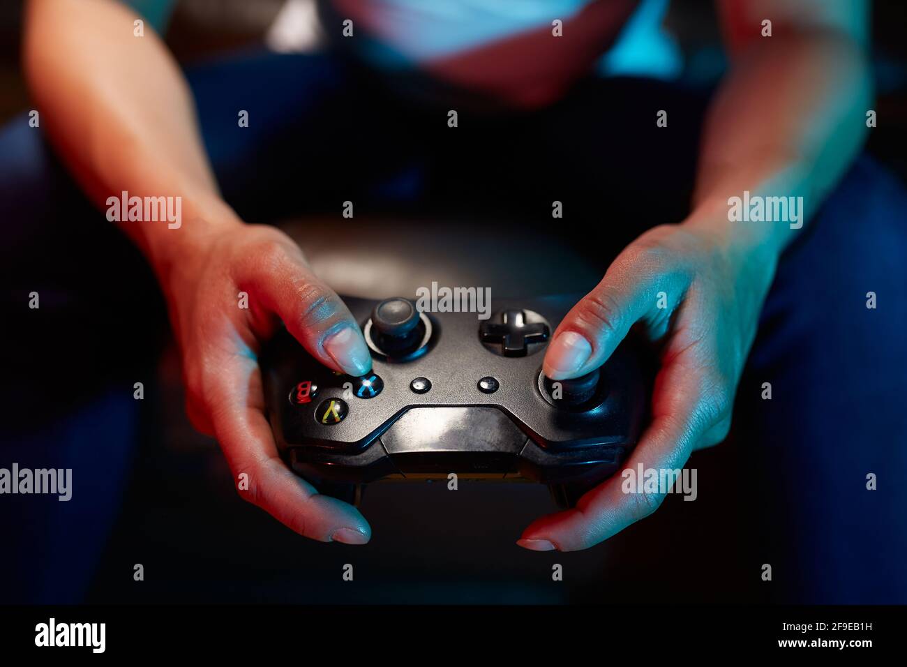 Rognez un joueur méconnaissable à l'aide du joy pad et jouez à un jeu vidéo dans la pièce sombre Banque D'Images