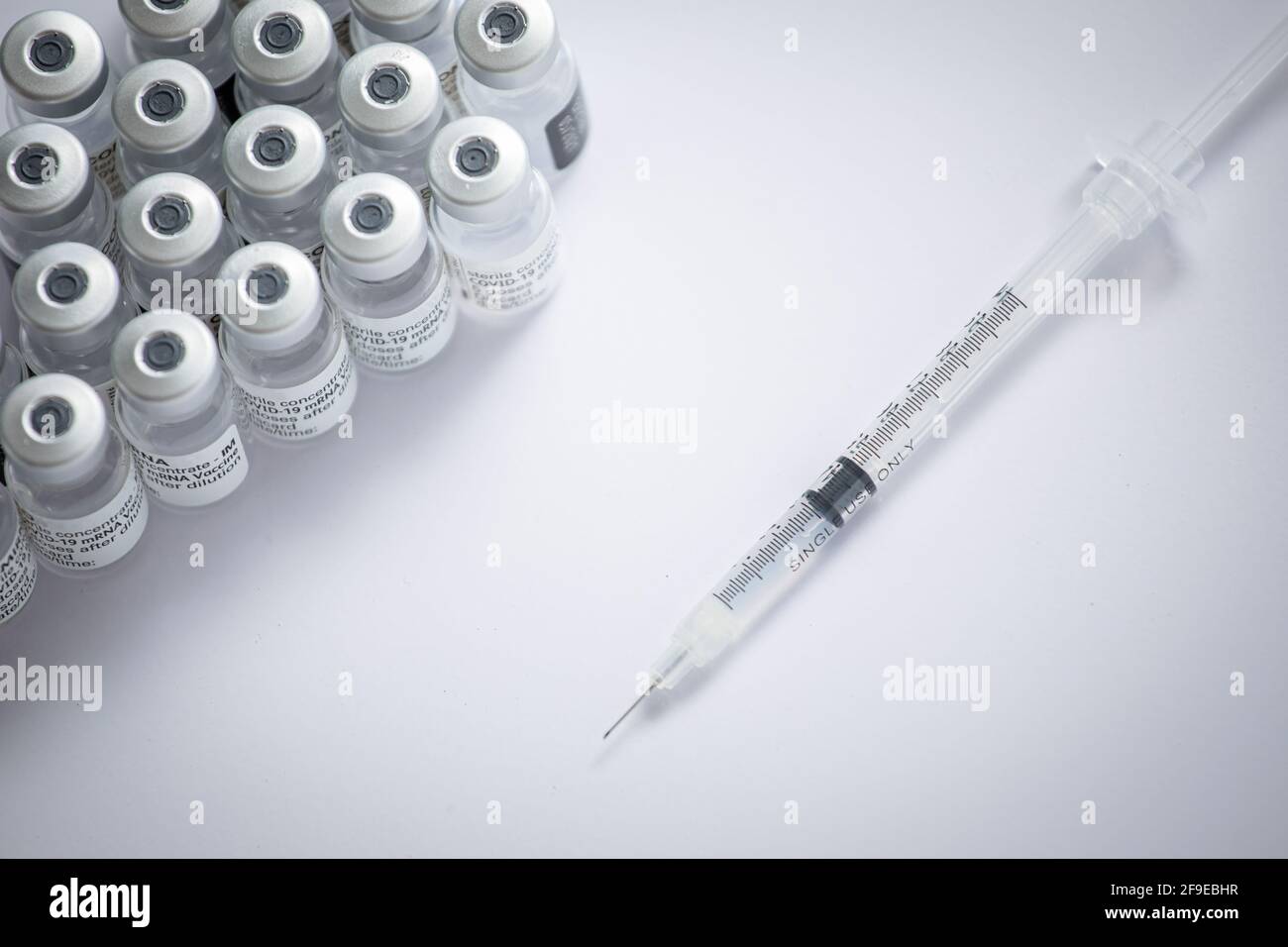 Gros plan de certains flacons avec le vaccin coronavirus avec une aiguille sur fond blanc Banque D'Images