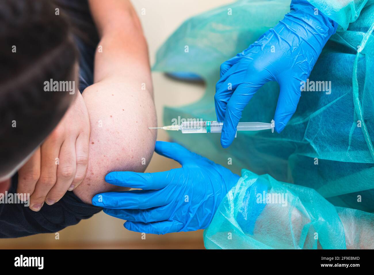 Spécialiste médical de la culture féminine en uniforme de protection, gants en latex et masque facial vaccinant un patient hispanique en clinique pendant l'outbrea du coronavirus Banque D'Images