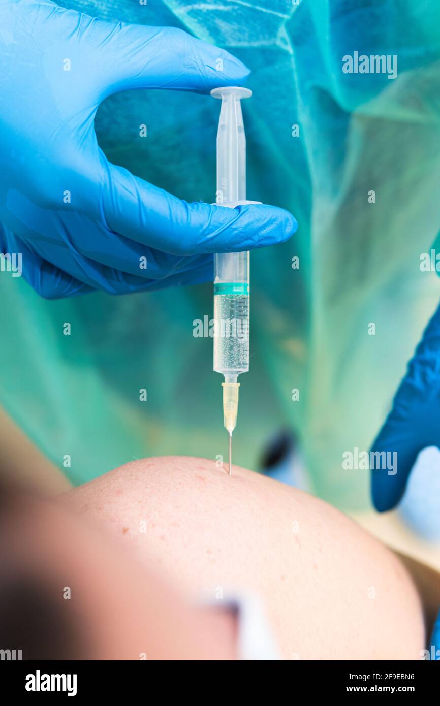 Spécialiste médical de la culture féminine en uniforme de protection, gants en latex et masque facial vaccinant un patient hispanique en clinique pendant l'outbrea du coronavirus Banque D'Images