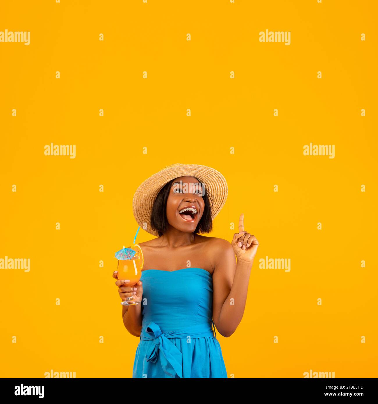 Femme noire excitée avec un délicieux cocktail d'été pointant vers le haut  de l'espace vide au-dessus de sa tête, orange studio arrière-plan Photo  Stock - Alamy