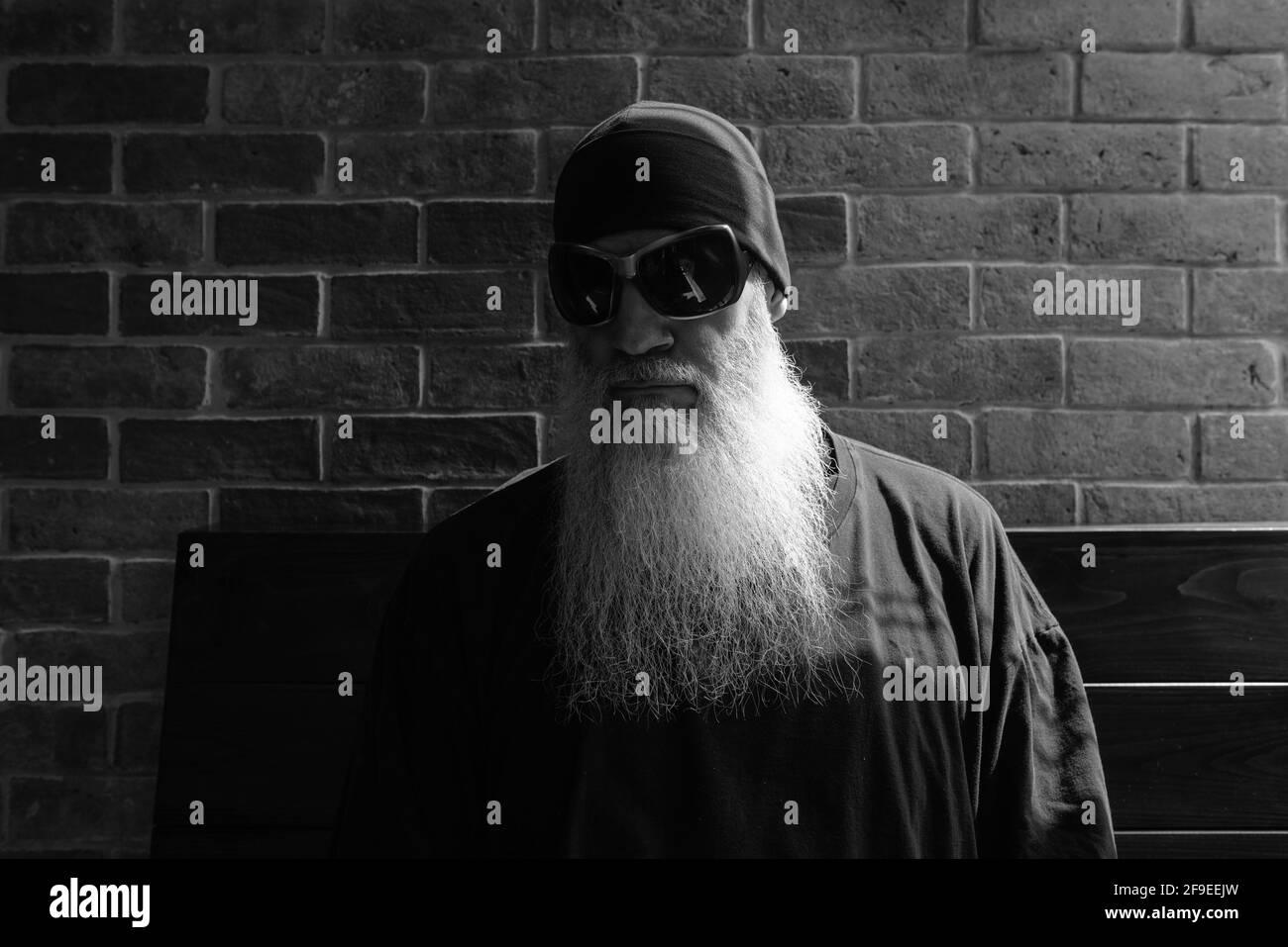 Portrait noir et blanc de l'homme mûr avec un long gris barbe portant un bonnet et des lunettes de soleil Banque D'Images