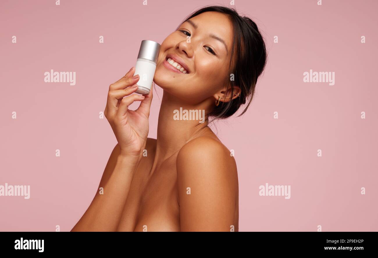 Femme asiatique aimant le nouveau produit de soins de beauté. Modèle féminin tenant un produit cosmétique. Banque D'Images