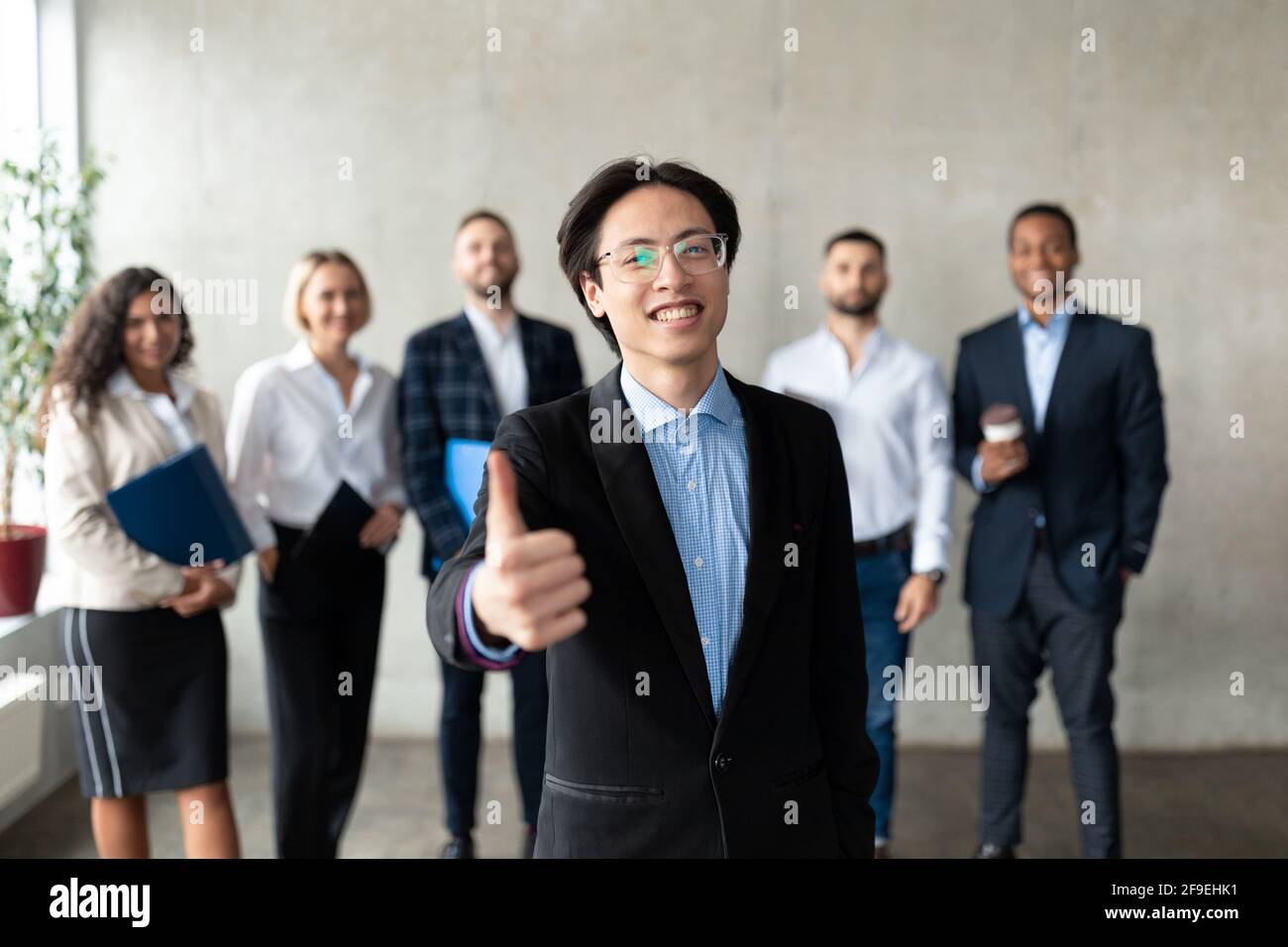 Homme d'affaires asiatique faisant la gestuelle avec l'équipe des employés au bureau Banque D'Images