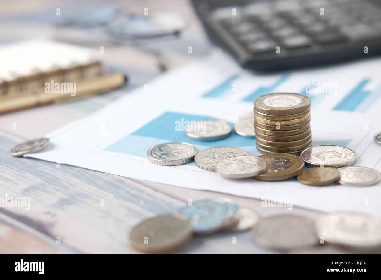 pile de pièces, graphique financier, calculatrice et bloc-notes sur la table Banque D'Images