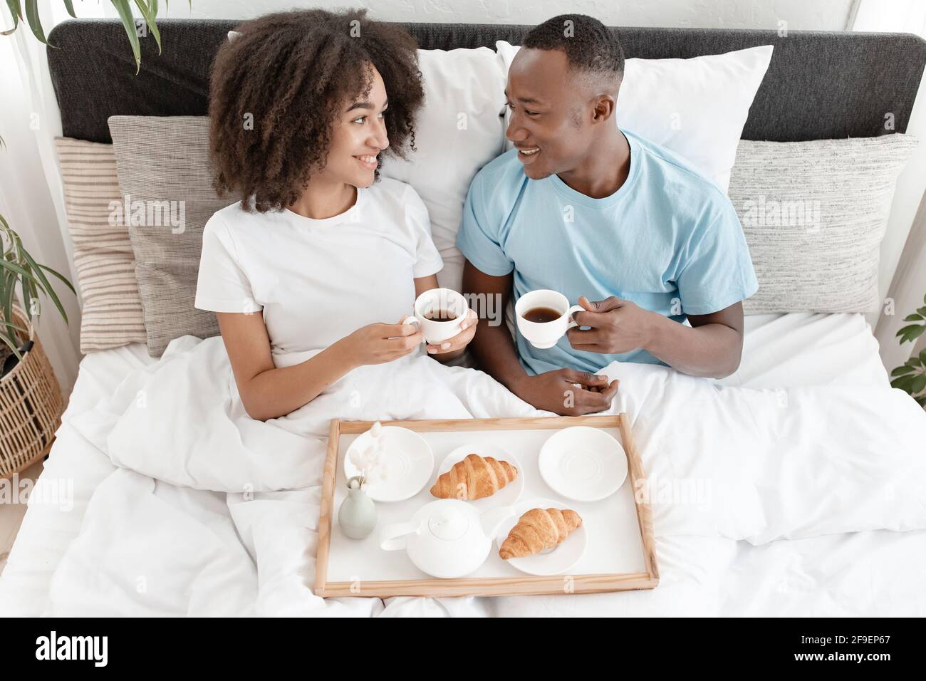 Beau matin et couple romantique amoureux prendre le petit déjeuner au lit, se reposer et se détendre à la maison Banque D'Images