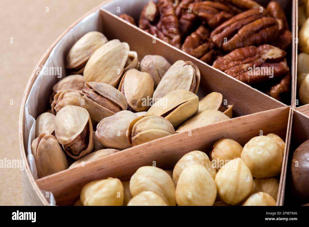 boîte en bois avec des cellules pour différents fruits à coque nourriture pour la nutrition des protéines saines pistache gros plan, personne. Banque D'Images
