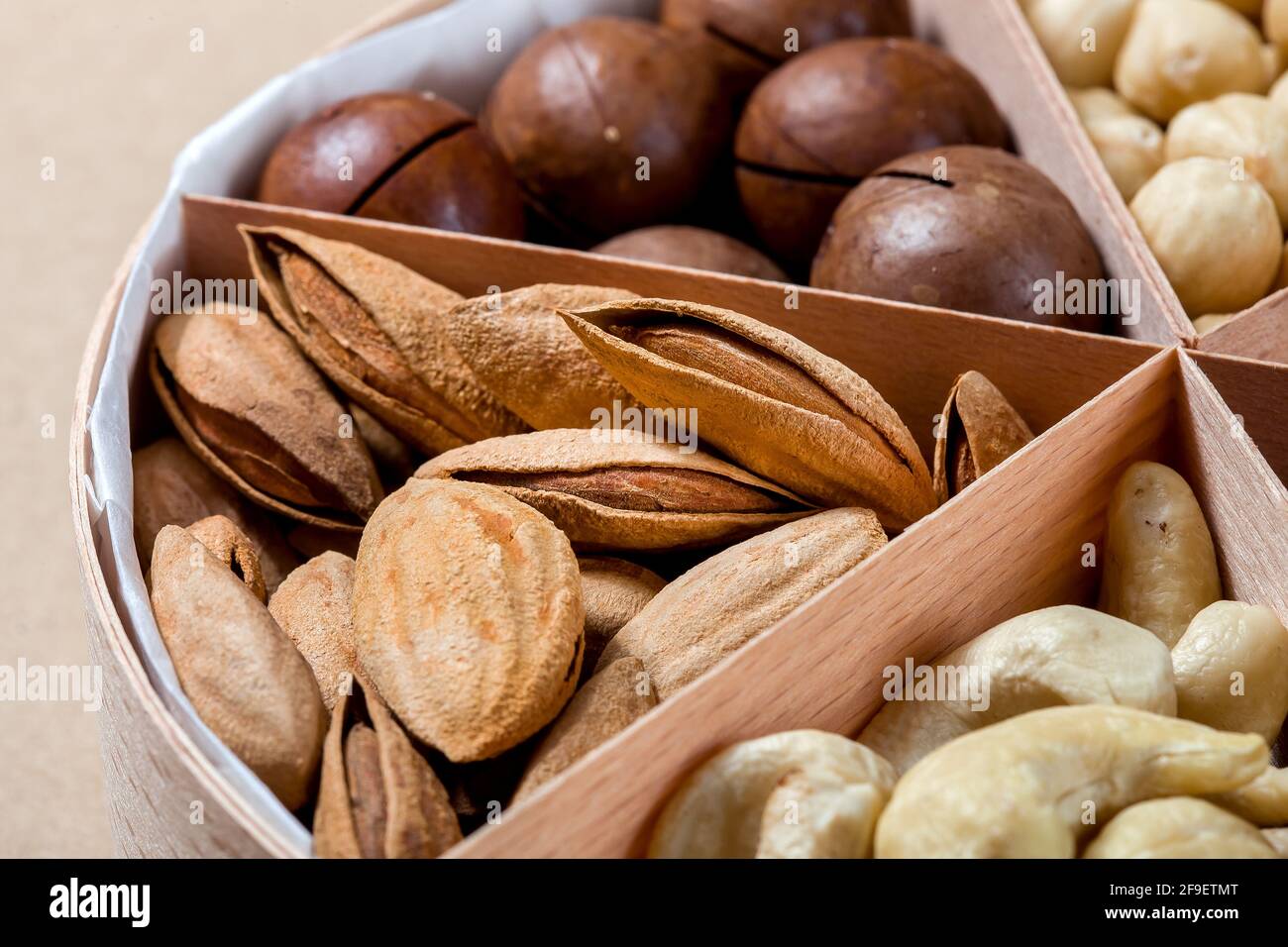 boîte en bois avec des cellules pour différents fruits à coque nourriture pour la nutrition saine des protéines gros plan amandes, personne. Banque D'Images