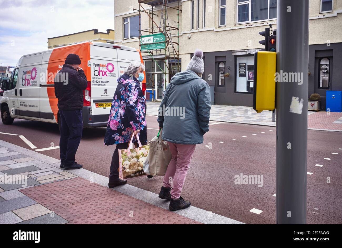 Masque portant des personnes âgées traversant la route à Douglas, île de Man Banque D'Images