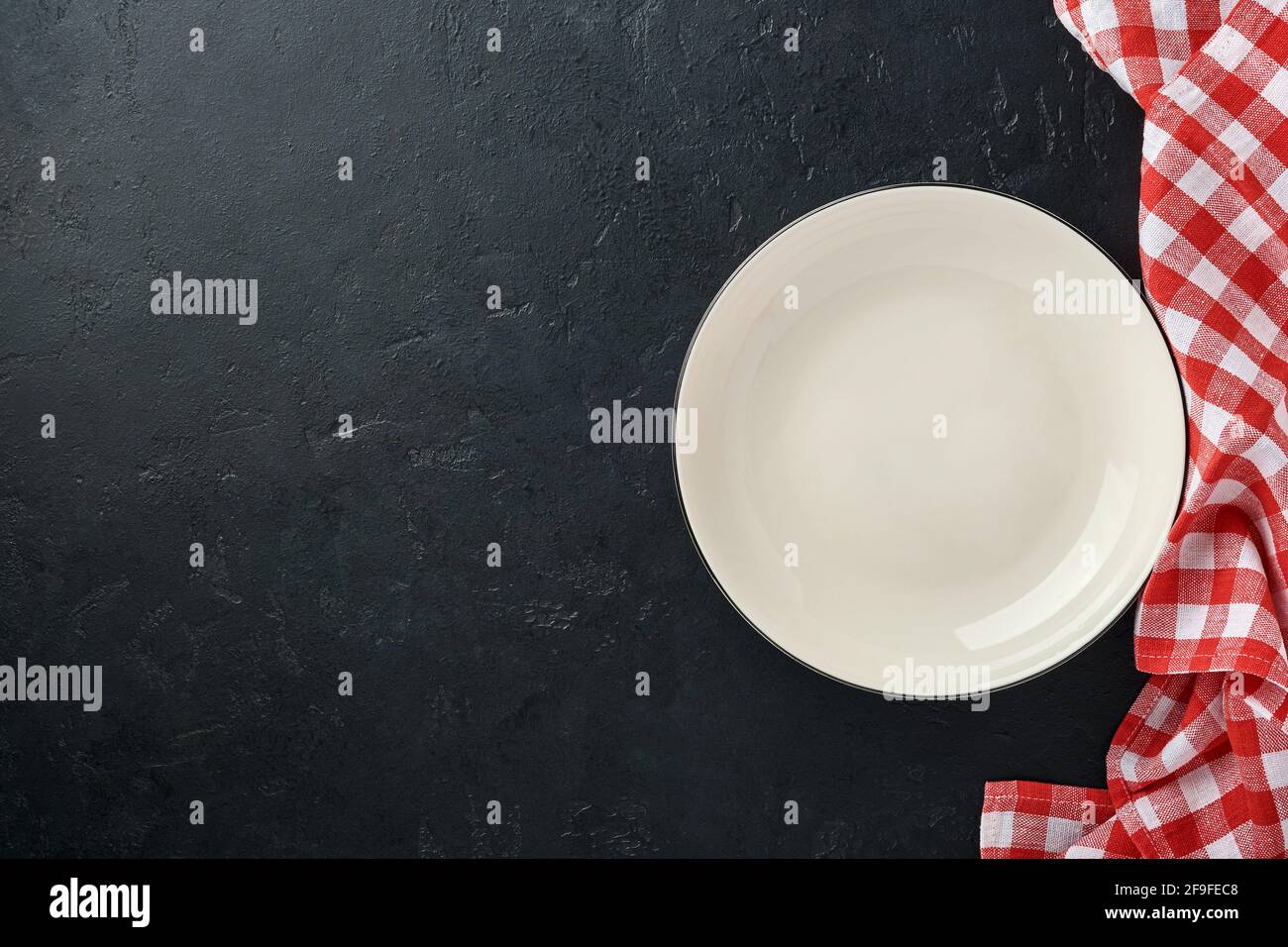 Table de cuisine avec plaque vide de couleur blanche, nappe rouge et espace pour votre recette ou votre menu. Vue de dessus. Maquette. Banque D'Images