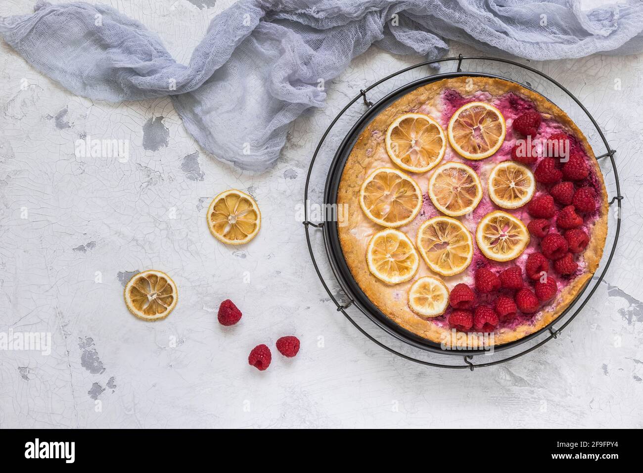 Gâteau au fromage aux framboises, tranches de citron séchées et tissu gris sur fond blanc, vue du dessus Banque D'Images