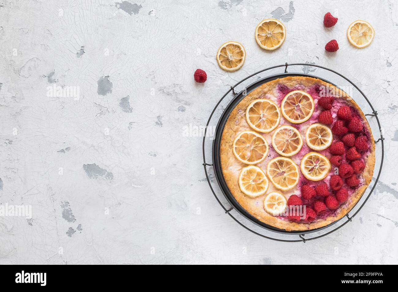Gâteau au fromage avec framboises et tranches de citron séchées sur fond blanc, vue de dessus avec espace de copie Banque D'Images