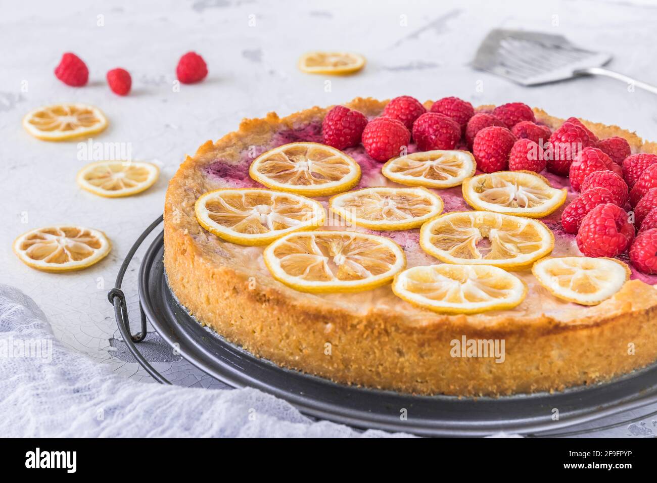 Gâteau au fromage avec framboises et tranches de citron séchées sur fond blanc, quelques framboises, tranches de citron et un serveur à gâteau couché sur la table. Gros plan. Banque D'Images