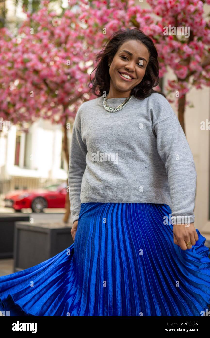 Un modèle portant un pull gris H&M avec une jupe longue d'Anthropologie  bleue et des chaussures Bershka argentées vues lors d'une séance photo de  style urbain à Bond Street, Londres Photo Stock -