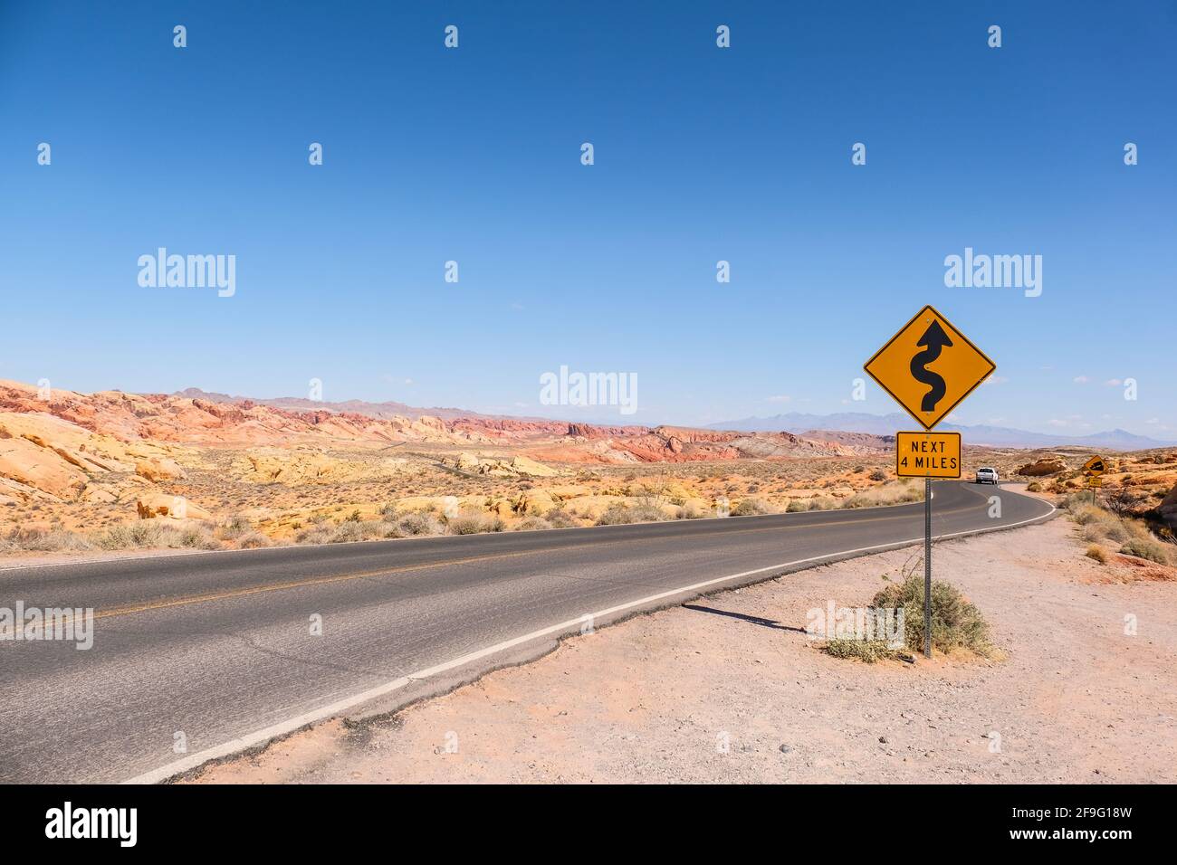 Un virage et tourner la route pour les 4 prochains miles Panneau près de l'autoroute avec le grès et le rocher de Red Aztec Formation au parc national de la Vallée de feu dans le Nevada Banque D'Images