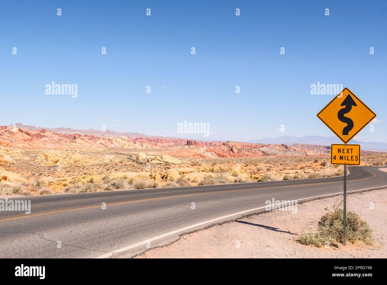 Un virage et tourner la route pour les 4 prochains miles Panneau près de l'autoroute avec le grès et le rocher de Red Aztec Formation au parc national de la Vallée de feu dans le Nevada Banque D'Images