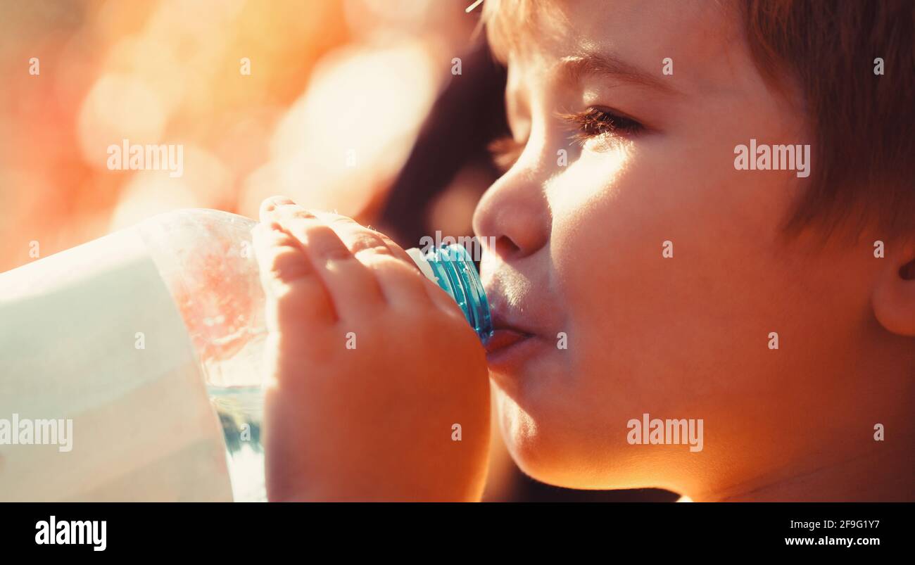 L'enfant boit de l'eau dans une bouteille tout en marchant, santé de bébé. Bouteille d'eau pour garçon. Jeune garçon tenant boire bouteille d'eau douce Banque D'Images