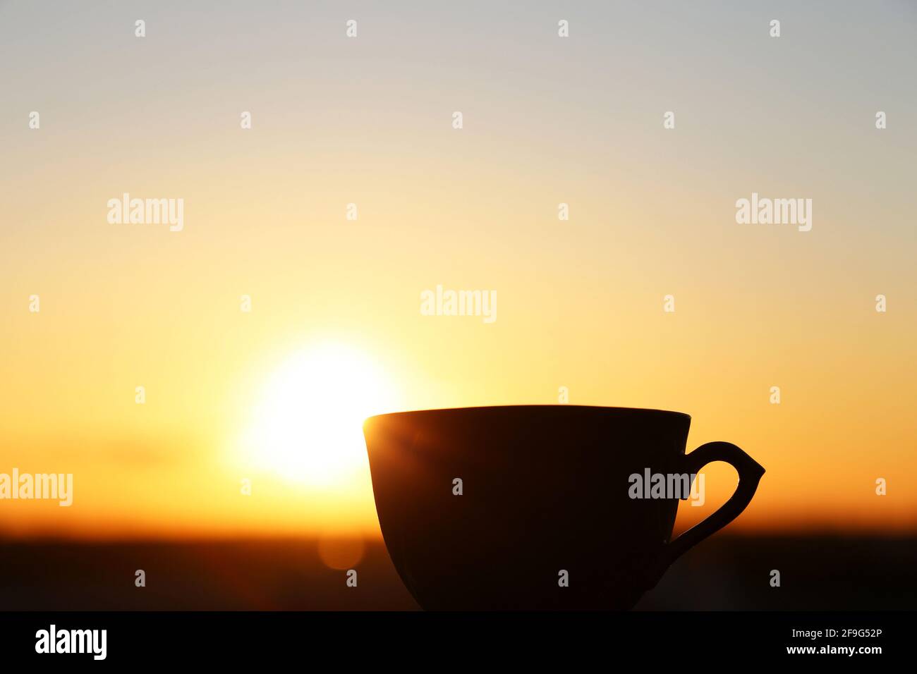 Silhouette de tasse de café sur fond de lever de soleil, départ frais le matin. Atmosphère chaleureuse, vue sur la ville depuis la fenêtre Banque D'Images