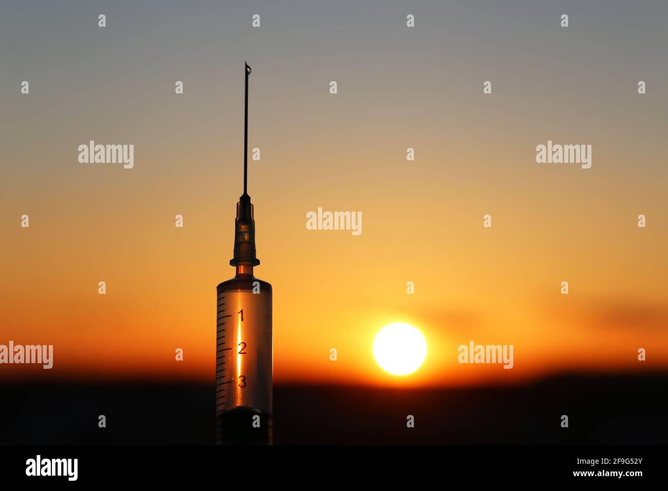 Silhouette de seringue médicale à la main sur fond de coucher de soleil. Concept de vaccination pendant la pandémie de Covid-19 Banque D'Images
