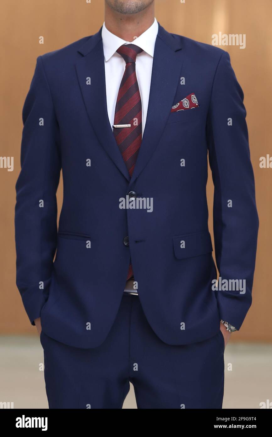 Un homme avec un costume bleu marine blanc chemise rouge cravate a rayures bordeaux et poche carree Photo Stock Alamy