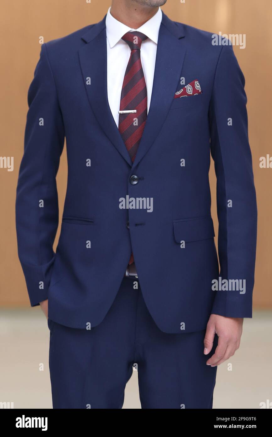 Un homme avec un costume bleu marine blanc chemise rouge cravate à rayures  bordeaux et poche carrée Photo Stock - Alamy