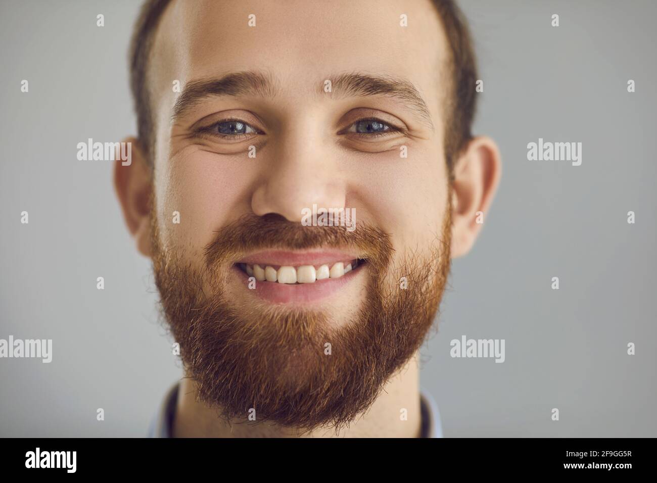 Gros plan portrait en studio d'un jeune homme barbu heureux et sympathique sourire à l'appareil photo Banque D'Images