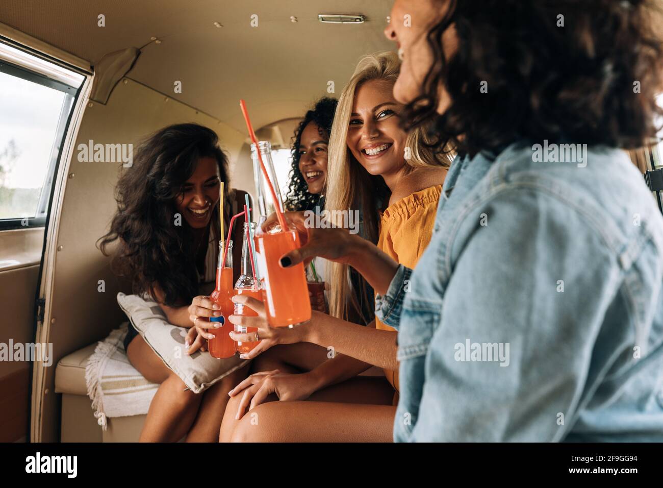 Quatre femmes buvant des cocktails dans une camionnette de camping en été Banque D'Images