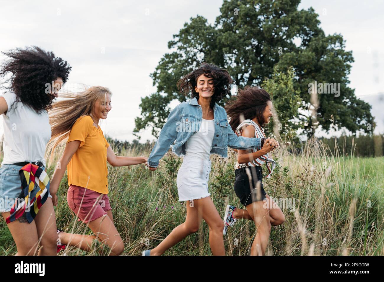 Groupe d'une femme heureuse qui court et saute à l'extérieur. Des amies qui s'amusent Banque D'Images