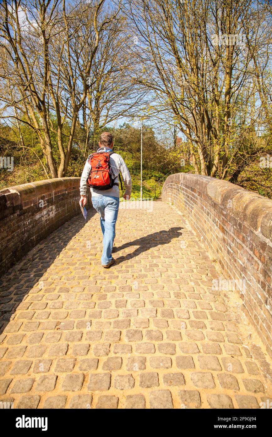 Homme routard qui marche au-dessus d'un vieux pont à cheval avec chariot de canal Au-dessus du canal Trent et Mersey à Kidsgrove Stoke on Trent Staffordshire Banque D'Images