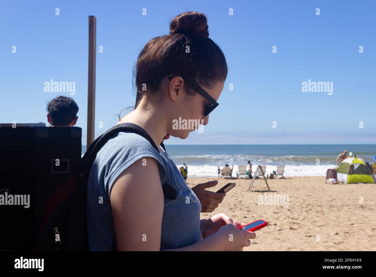 Jeune femme avec des lunettes et un téléphone portable sur la plage. Banque D'Images