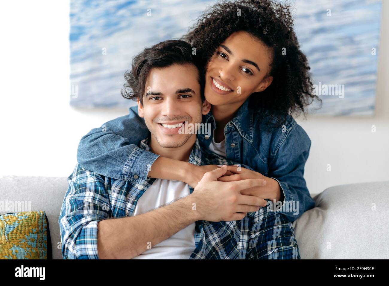 Portrait d'un couple de course mixte heureux amoureux. Jolie fille curly afro-américaine et un type hispanique séduisant tendinant les uns les autres, regardant l'appareil photo, souriant, famille heureuse Banque D'Images