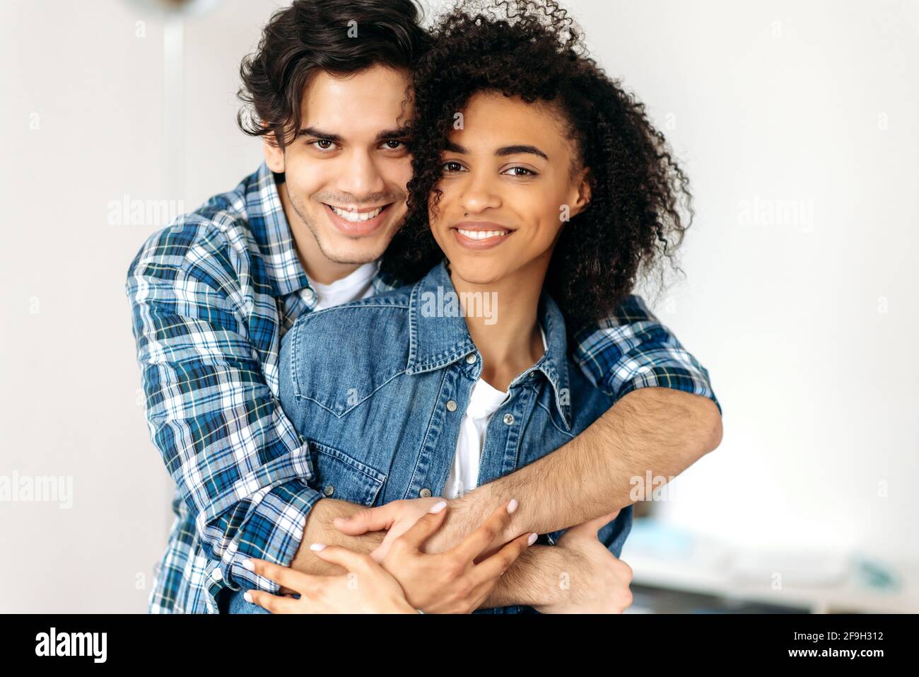 Portrait d'un jeune heureux couple multiracial amoureux. Jolie fille maurique afro-américaine et un type hispanique attrayant s'embrassant les uns les autres, regardant la caméra, souriant, heureux ensemble Banque D'Images