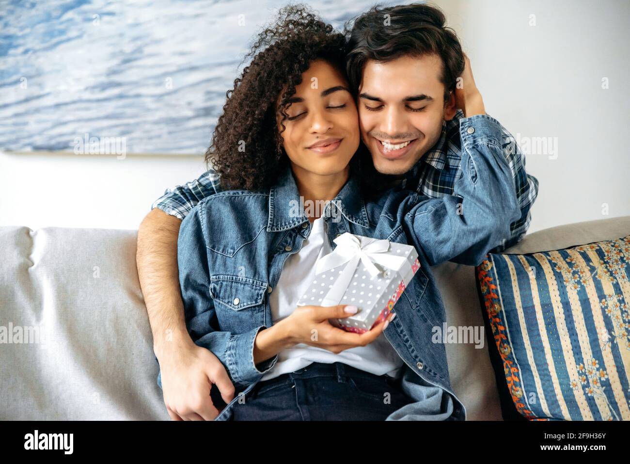 Cadeau D Anniversaire Un Homme De Race Mixte Donne Une Boite Avec Un Cadeau A Sa Jolie Amie Afro Americaine Bien Aimee Fait Une Surprise S Embrassant Sur Un Canape A La Maison Une Relation Heureuse