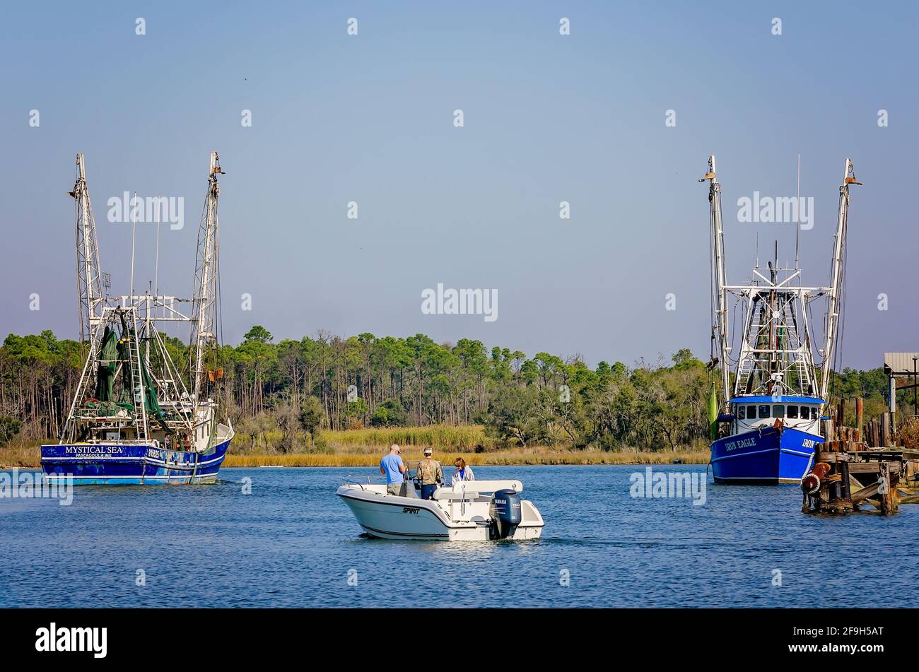 Une famille dans un bateau de pêche passe entre deux bateaux à crevettes, “Mystique Sea” et “Iron Eagle”, 23 novembre 2012, à Bayou la Berre, Alabama. Banque D'Images