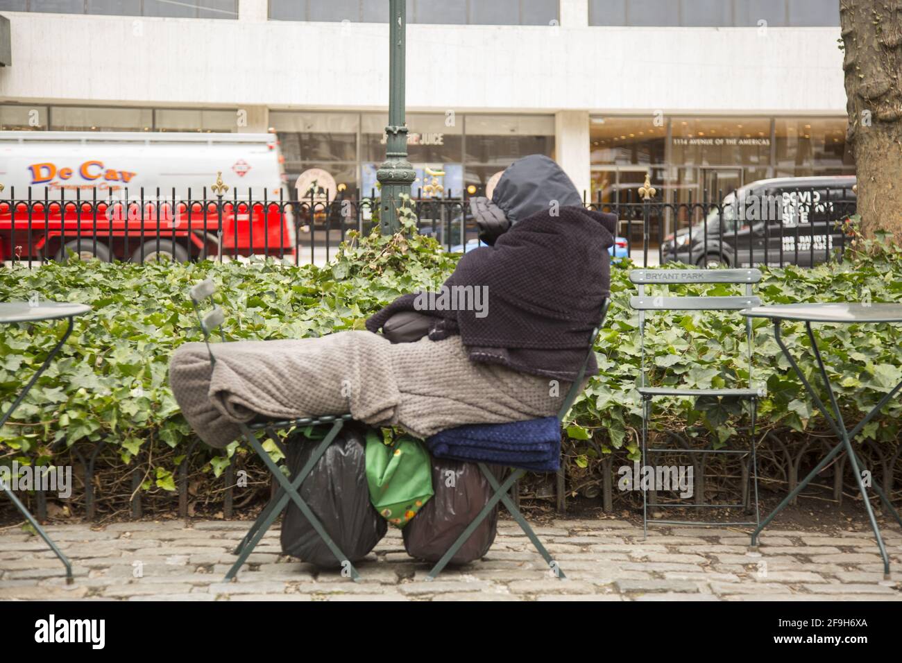 La personne sans domicile s'est enveloppée pour rester au chaud, dormant sur des chaises au Bryant Park le long de la 42e rue dans Midtown Manhattan, New York. Banque D'Images