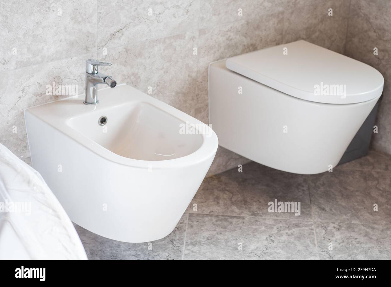 bidet et toilettes muraux blancs, carrelage en céramique grise dans la salle de bains Banque D'Images
