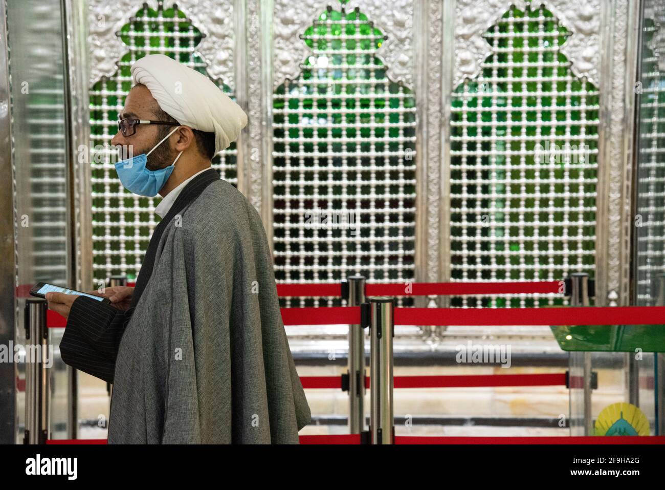 Téhéran, Iran. 18 avril 2021. Un religieux iranien portant un masque protecteur marche près du sanctuaire de Shah Abdol-Azim.le sanctuaire de Shah Abdol-Azim est protégé par une bande rouge pour empêcher les visiteurs de le toucher et de l'épidémie de COVID-19 . (Photo de Sobhan Farajvan/Pacific Press) crédit: Pacific Press Media production Corp./Alay Live News Banque D'Images