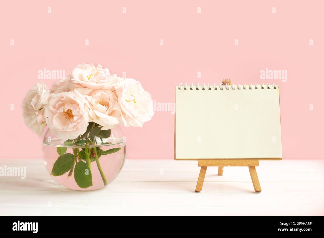 Roses de jardin rose tendre dans un vase transparent et un Easel avec papier blanc pour l'écriture de souhaits. Saint-Valentin, Pâques, anniversaire, Joyeux Fête des femmes, Fête des mères Banque D'Images