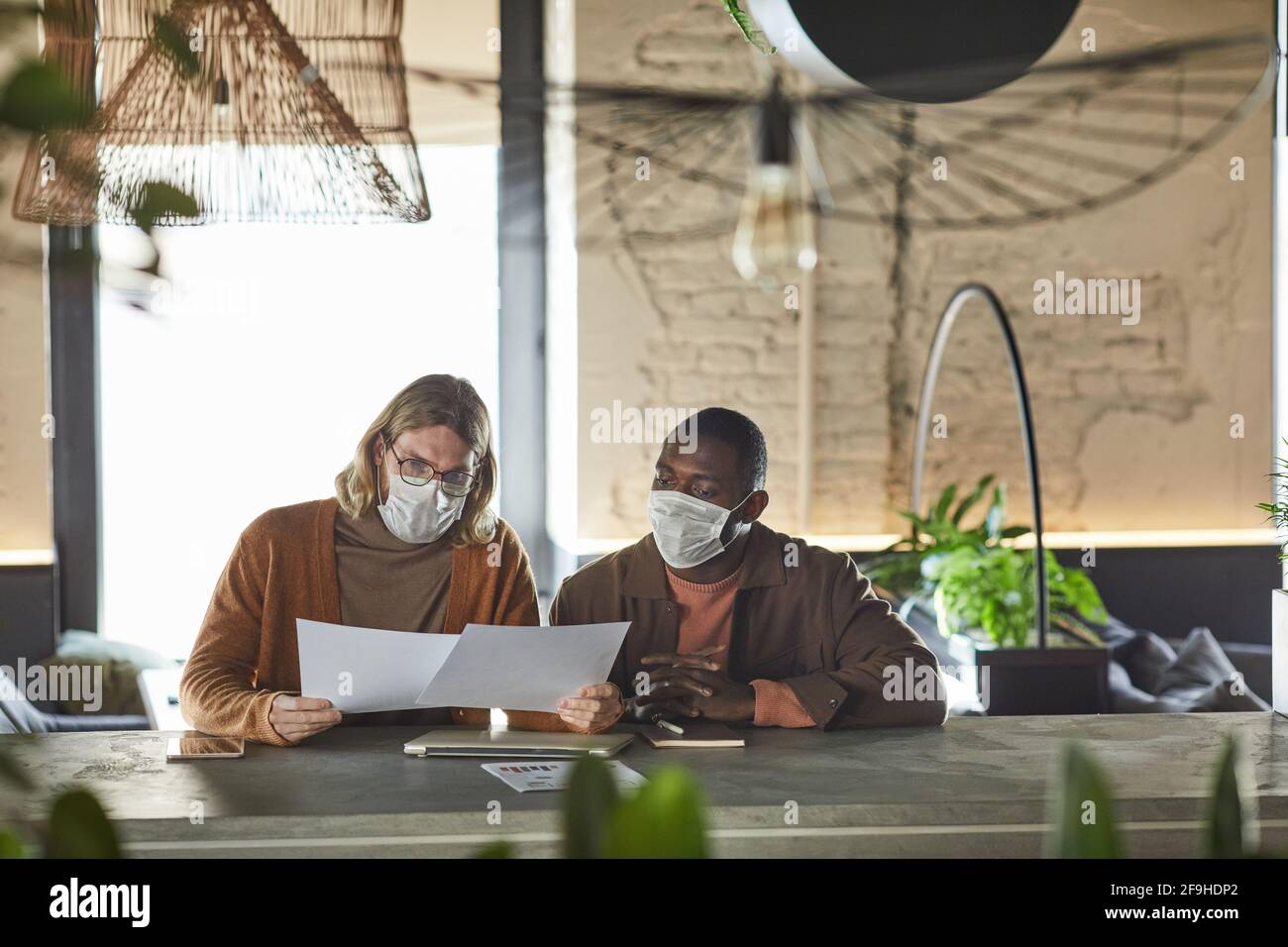Portrait de face de deux hommes collaborant sur le projet pendant une réunion d'affaires et portant des masques à l'intérieur du bureau ou du café, espace de copie Banque D'Images