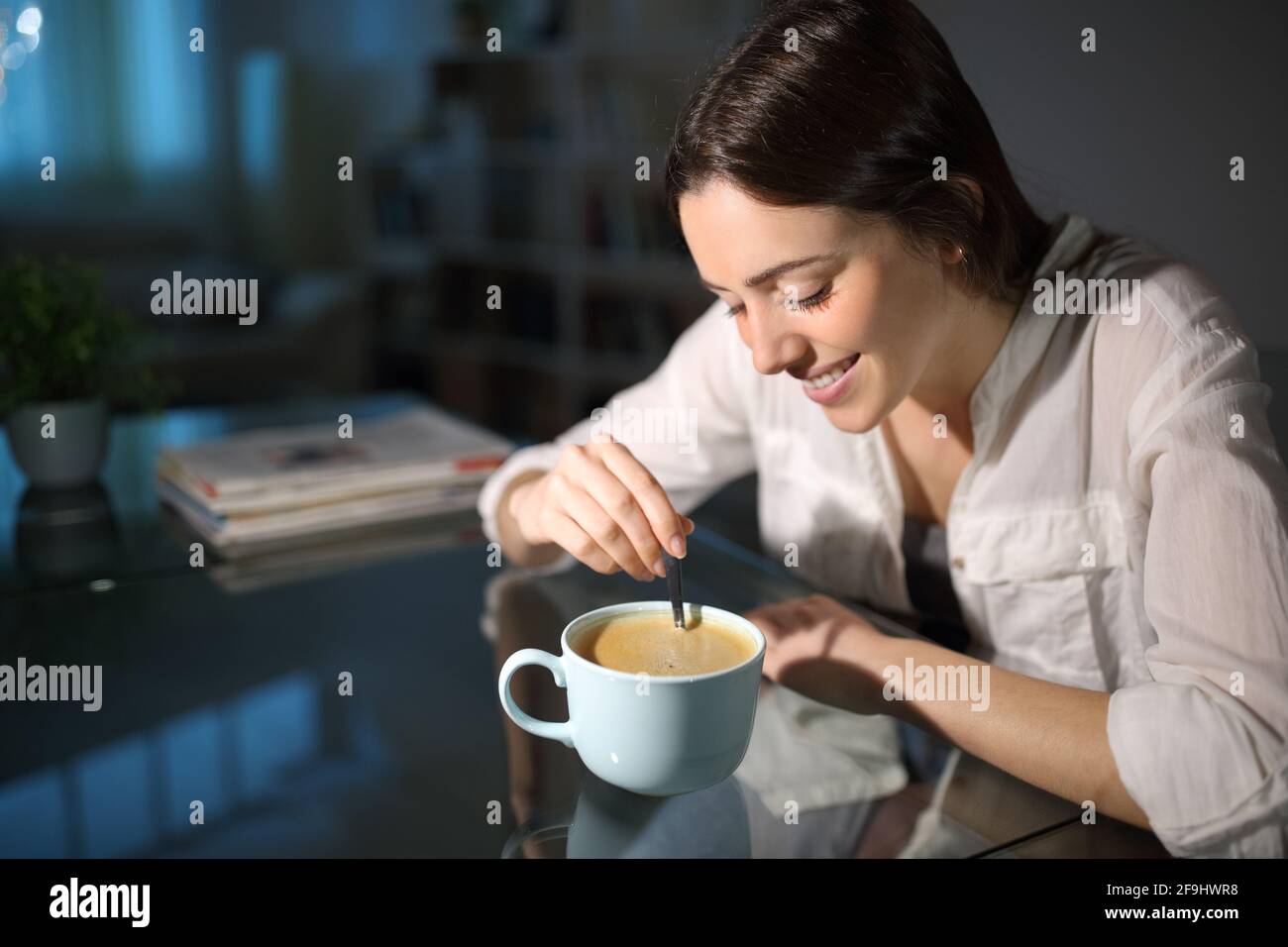 Bonne femme pensive remuant café décaféiné dans la nuit à accueil Banque D'Images