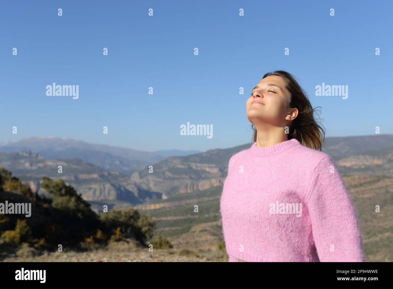 Femme détendue en rose respirant de l'air frais dans la montagne Banque D'Images