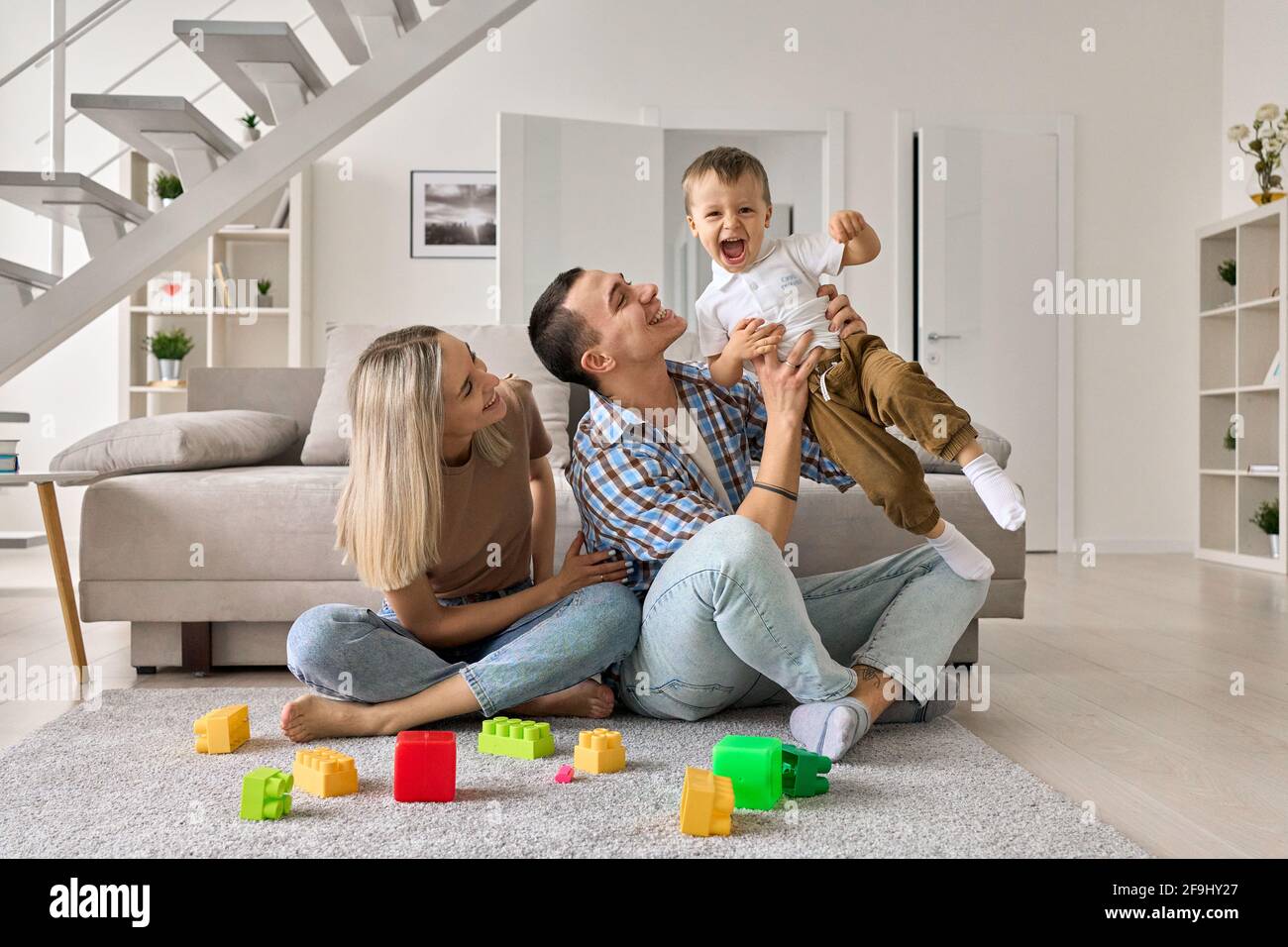 Un jeune couple heureux s'amuser avec un petit garçon mignon dans un salon moderne. Banque D'Images