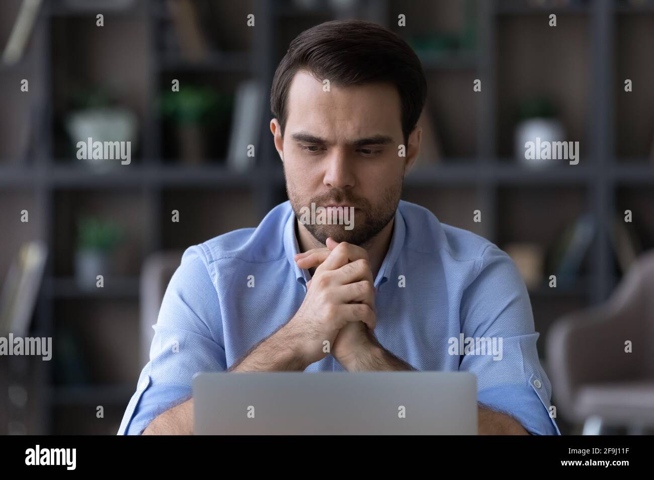 Un homme pensif travaille sur un ordinateur portable en pensant au problème Banque D'Images