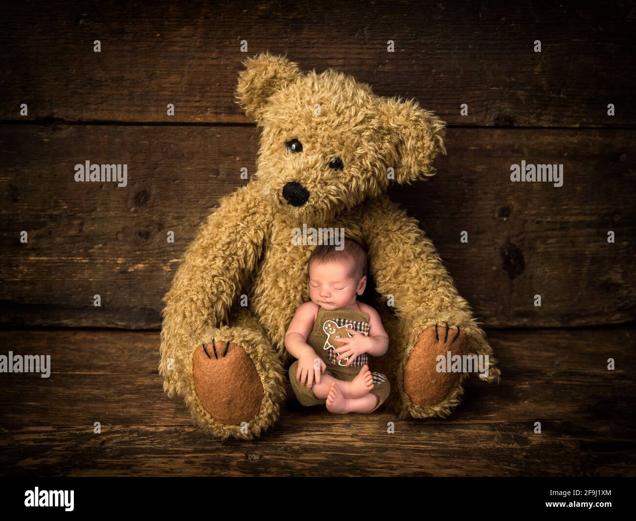 Bébé tenant un biscuit de pain d'épice dormant dans les bras de la mère ours en peluche Banque D'Images