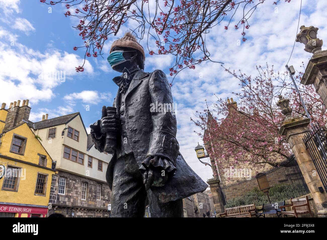 Edinburgh, Royaume-Uni. 19 avril 2021 photo : avec les prévisions météorologiques pour la semaine prochaine en Écosse, la statue de Robert Fergusson sur le Royal Mile d'Édimbourg est enveloppée d'un chapeau de laine tandis que les cerisiers commencent à fleurir au-dessus. Crédit : Rich Dyson/Alay Live News Banque D'Images