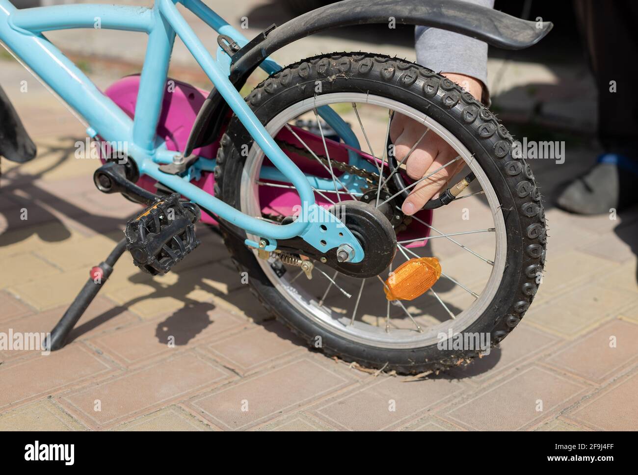 les hommes pompent la roue sur un vélo pour enfants. Pompage d'air dans une roue de vélo. Gros plan Banque D'Images