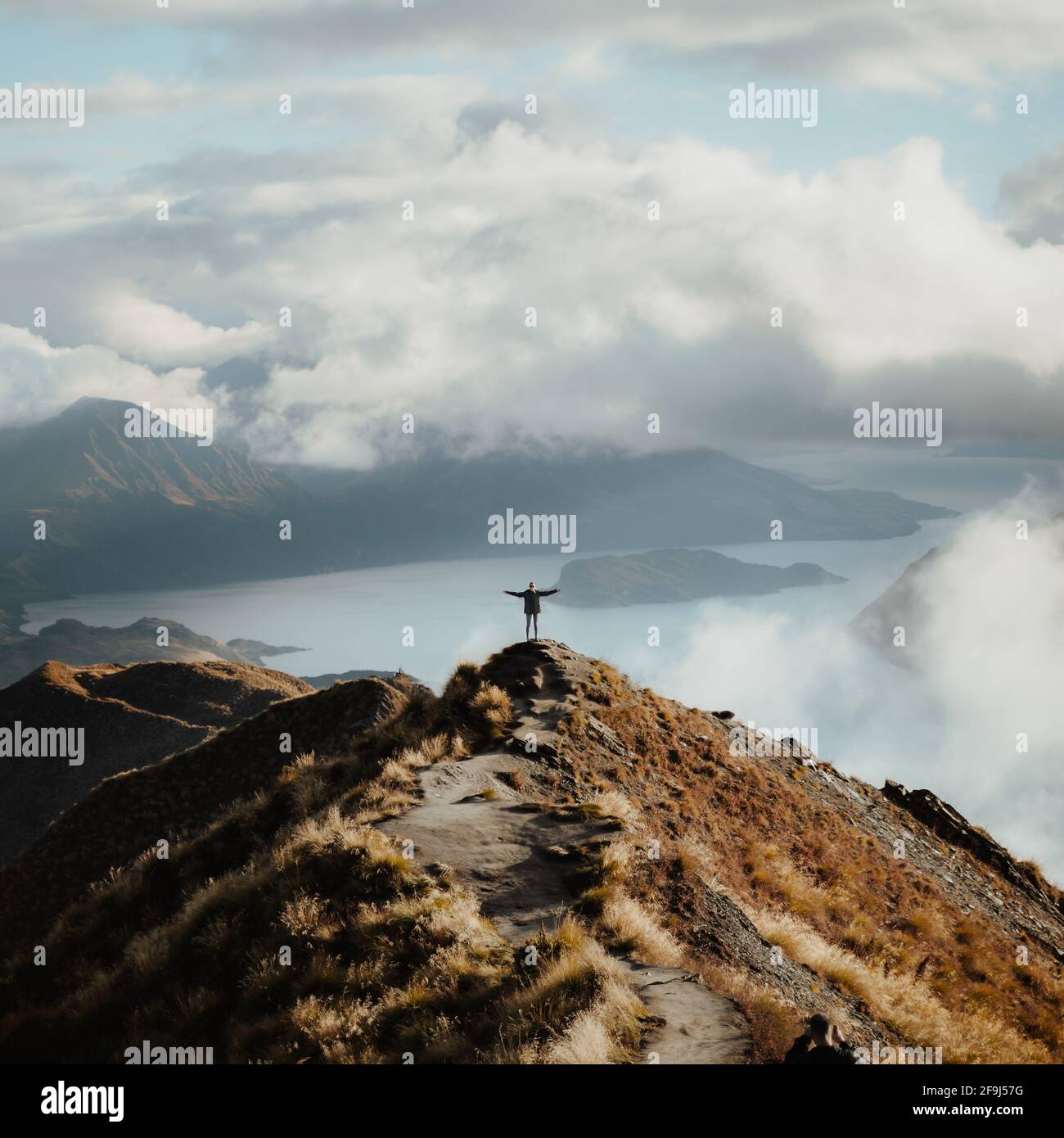 Homme avec les mains larges ouvertes debout au sommet de une montagne  profitant de la vue incroyable d'un lac Photo Stock - Alamy